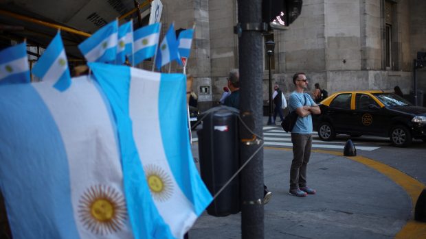 Muž stojí u pouličního obchodu s argentinskými vlajkami v centru Buenos Aires.