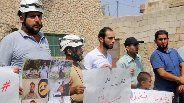 Demonstranti v syrském Idlíbu drží cedule s portréty sedmi členů Bilých přileb, které zastřelili neznámí útočníci. Maskovaní ozbrojenci pak zmizeli s vysílačkami a dalším zabaveným vybavením svých obětí. 13. srpna 2017.