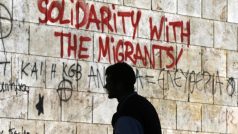 Řecko, imigrace. Muž v Aténách prochází kolem nápisu vyzývajícího k solidaritě s běženci.