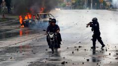 Policista míří zbraní na muže na motorce během protestů proti nikaragujskému prezidentovi Danielu Ortegovi