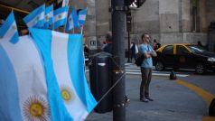 Muž stojí u pouličního obchodu s argentinskými vlajkami v centru Buenos Aires.