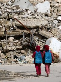 Děti procházejí zničenou čtvrtí syrského Aleppa